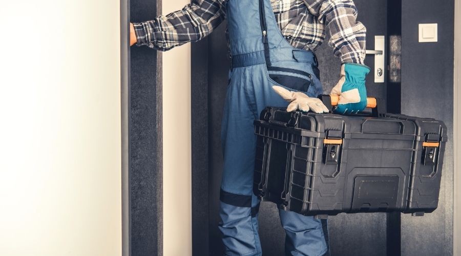 Worker in gloves with toolbox in HVAC service area at Tiger Temperature, Thibodaux, LA, prepared for maintenance tasks.