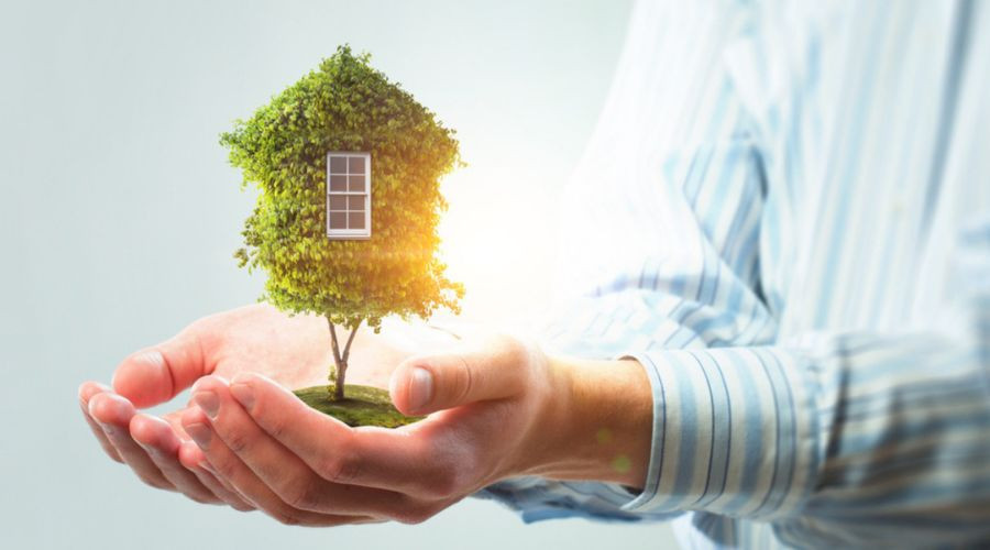 Hands nurturing a house made of greenery, symbolizing HVAC solutions for sustainable home environments.